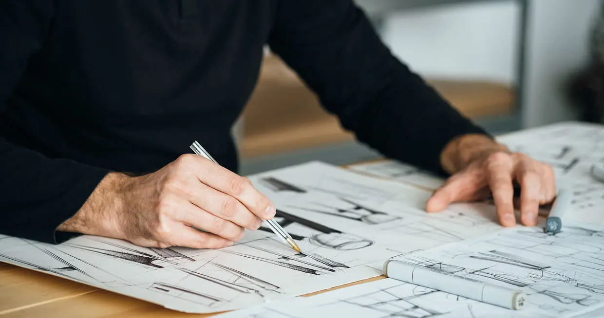 製図用紙にペンでスケッチを描く人物の手元の様子