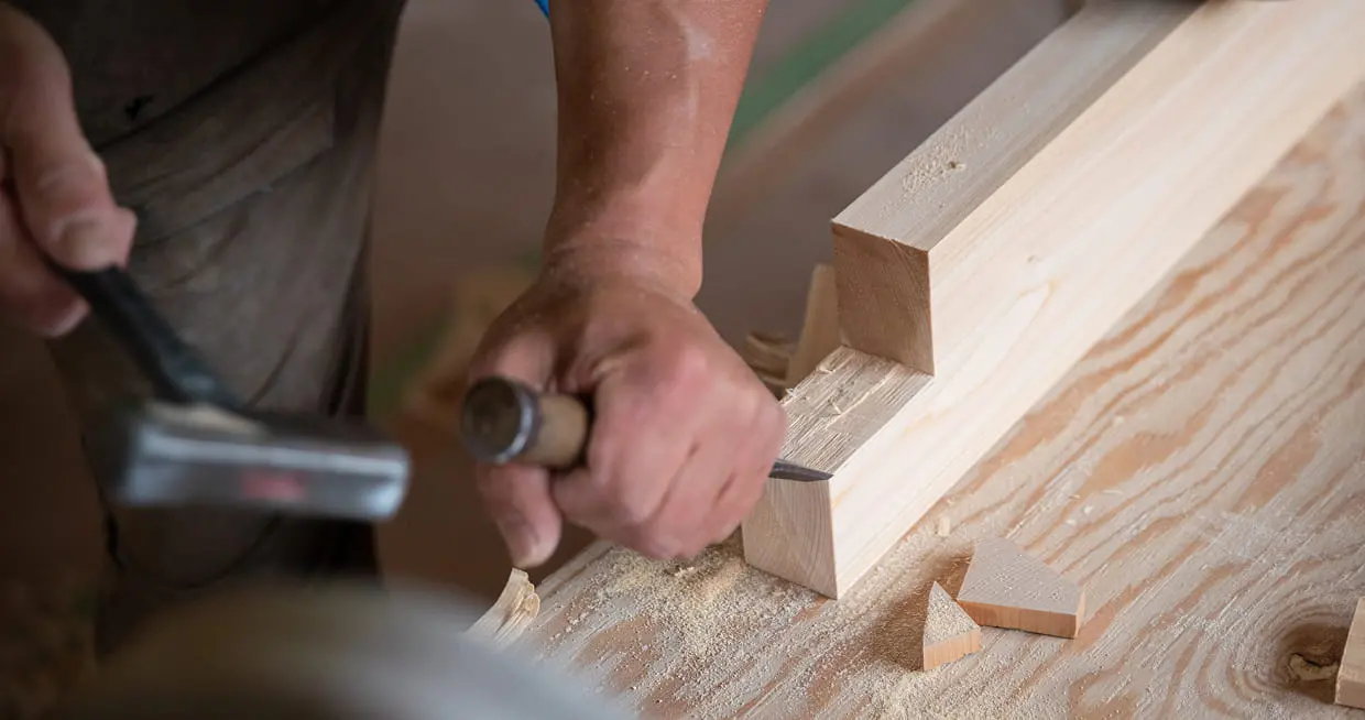 木材をノミと金槌で加工している大工の手元のクローズアップ