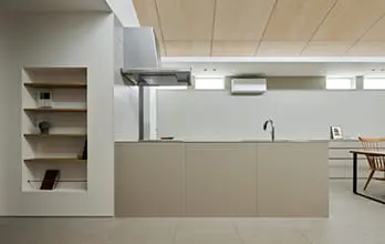 ベージュのフラットなアイランドキッチンが中心に配置されたシンプルな空間