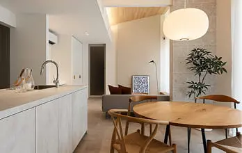 を基調としたキッチンと木製の丸テーブルが配置されたダイニング