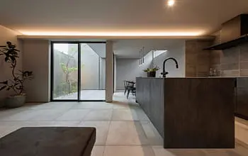 ダークトーンのアイランドキッチンと開放的な中庭が調和した空間